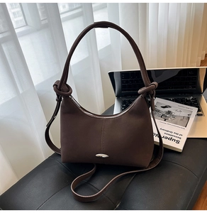 Detail of dark brown crescent shoulder bag with matte texture and decorative knots
