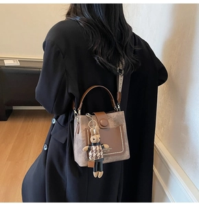 Detail of a brown bucket bag featuring pearl accents and a stylish plush bunny charm