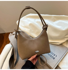 Detail of khaki soft leather hobo bag with silver buckle and decorative knot strap