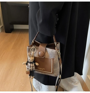 Close-up of brown bucket bag with vintage branding and checkered rabbit plush charm