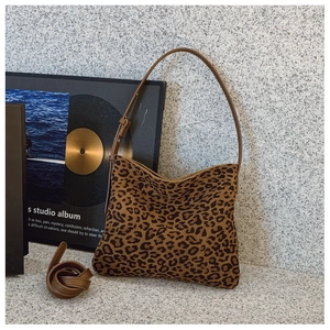 Dettaglio borsa a spalla leopardata con tracolla in pelle marrone su sfondo strutturato