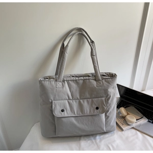 Close-up of light gray nylon tote bag with pocket in a lifestyle student desk setting