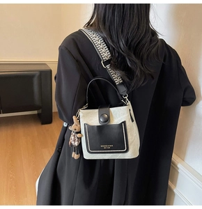 Detail of cream bucket bag featuring pearl-studded pocket and rabbit charm accessory