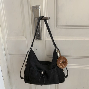 Detalle de bolso hobo negro con bolsillo de cordón y colgante de peluche de donut