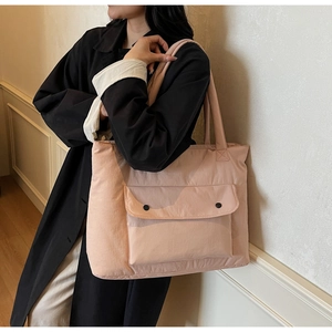 Detail of light pink large tote bag with front flap pocket and black buttons on the canvas
