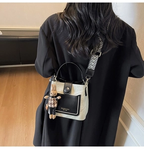 Chic beige bucket bag with black flap, pearl trim and rabbit charm on wide strap