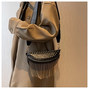 Close-up of black leather chest bag with silver studs, gold tassels and chevron strap