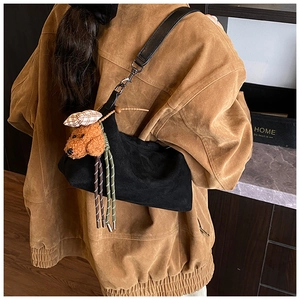 Detail of soft black crossbody pillow bag featuring a cute brown teddy bear plush charm