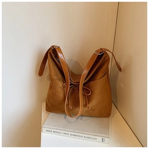 Gros plan d'un sac à main en daim marron avec nœud décoratif et finitions soignées