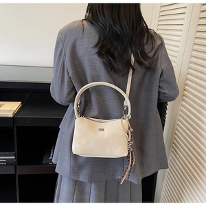 Detail of cream tote bag with suede texture, top handle and decorative silk scarf