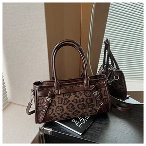Detail einer Handtasche mit Leopardenmuster, braunem Lederbesatz und Metallschnallen