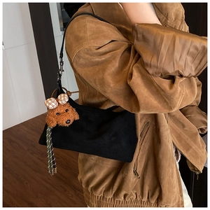 Detail of black matte underarm bag with a cute brown teddy dog plush pendant
