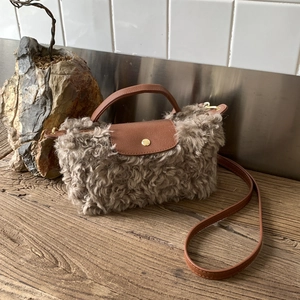 Detail of faux fur crossbody bag with brown leather strap and gold snap closure