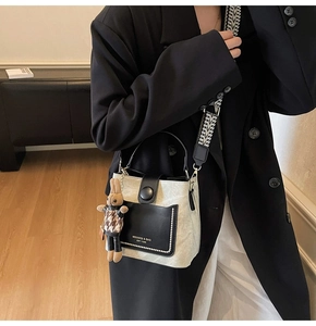 Detail of a beige bucket bag with black pocket and stylish geometric wide strap