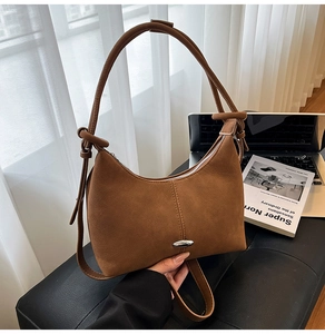 Close-up of caramel suede crescent shoulder bag with knotted strap and metal clasp detail