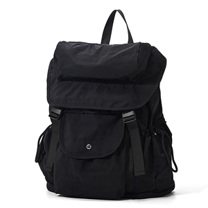 Dettaglio dello zaino in nylon nero con doppie cinghie a fibbia e tasche con coulisse