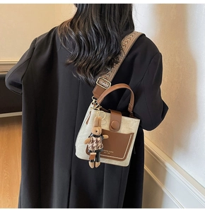Detail view of stylish bucket bag with geometric strap and cute rabbit pendant