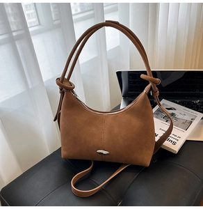 Detail of a brown suede hobo bag featuring silver metal trim and knotted handle design