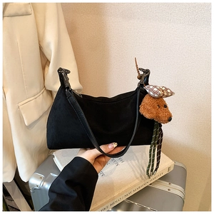 Detail of black suede hobo bag with cute brown teddy bear charm and metal buckle