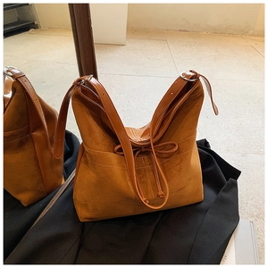 Détail du sac cabas en suède avec décoration de nœud en cuir et bandoulière lisse