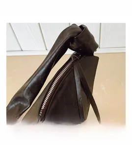 Macro view of dark brown leather handbag featuring knotted strap and metallic zipper detail