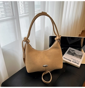 Detail of light brown suede crescent shoulder bag with metallic buckle and knotted strap