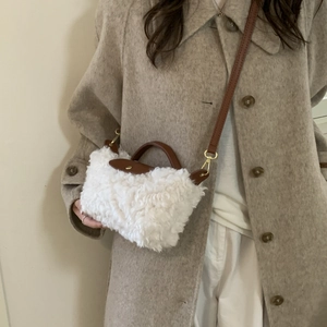 Detail of white faux fur crossbody bag with brown leather trim and gold metal hardware