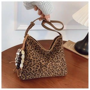 Dettaglio della borsa hobo leopardata con ciondolo di perline su sfondo vintage