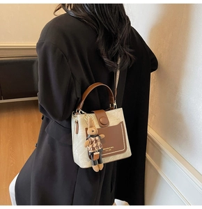 Detail of contrast bucket bag with leather pocket and plaid bunny charm on black blazer