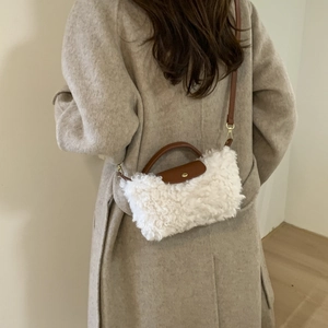 Detail of white faux fur crossbody bag with brown leather strap on beige cashmere coat