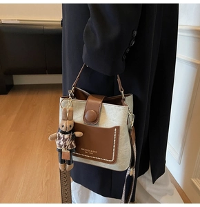 Detail of canvas bucket bag with leather pocket and cute bunny charm accessory