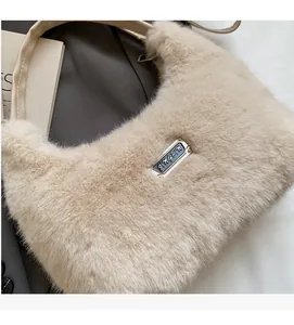 Dettaglio della borsa in peluche morbido con manico in pelle e placca logo