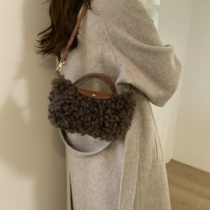 Detail of dark brown faux shearling crossbody bag with leather flap and gold hardware
