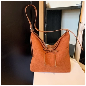 Gros plan du sac cabas en suède caramel avec surpiqûres blanches et détail de nœud