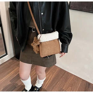 Close-up of brown suede bucket bag with white fleece trim and cute plush bear charm