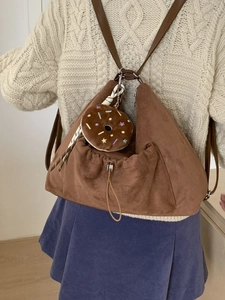 Bolso de hombro de gamuza marrón con colgante de dona en modelo con suéter de punto