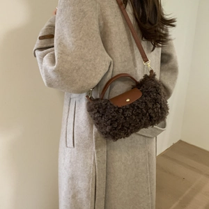 Close-up of brown plush crossbody bag with leather flap and golden hardware details
