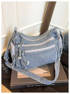 Detail of light blue denim crossbody bag with multi-zipper pockets and adjustable strap