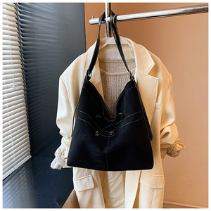 Détail du sac porté épaule noir vintage avec surpiqûres sur une veste beige