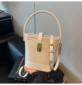 Detail of cream bucket bag with gold lock fastener and adjustable thin shoulder strap