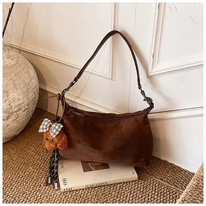 Detail of dark brown suede shoulder bag with cute teddy dog plush pendant and zipper