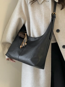 Vintage black hobo bag with heart charm shown on model in a cream wool coat