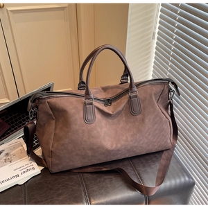 Gros plan d'un grand sac de voyage marron avec poignées et bandoulière réglable amovible
