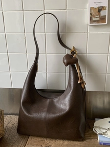 Retro dark brown large Hobo shoulder bag with heart pendant and fringe on wooden table