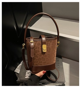 Detail of dark brown leopard print bucket bag with gold lock on luxury books