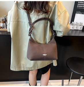 Rear view of model wearing a dark brown matte leather shoulder bag with a knotted handle