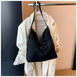 Détail du grand sac cabas en daim noir avec surpiqûres blanches et nœud décoratif