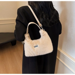 Borsa beige in finta pelliccia con logo argento indossata su cappotto nero lungo