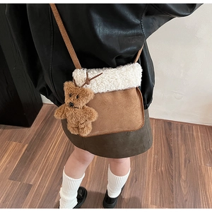 Dettaglio della borsa a tracolla in pelle scamosciata marrone e sherpa con orsetto di peluche