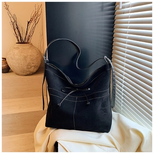 Détail du sac cabas en suédine noire avec surpiqûres blanches et détail de nœud élégant